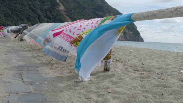 在傍晚的海滩上的风中摇曳的木栏杆上挂着五颜六色的海滩毛巾 — 图库视频影像
