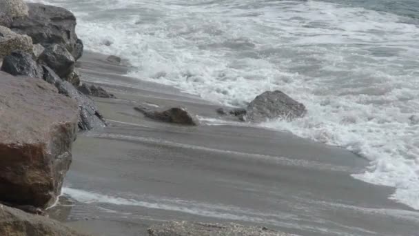 Zee golven bewegen op zanderige kust met rotsen produceren licht schuimend wildwater — Stockvideo