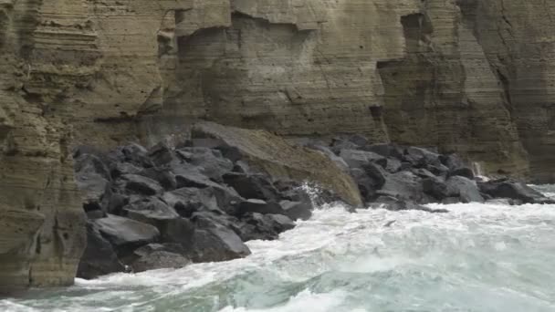 Потужні хвилі, що вражають скелясті скелі і падають, щоб утворити тріщини і бризки — стокове відео