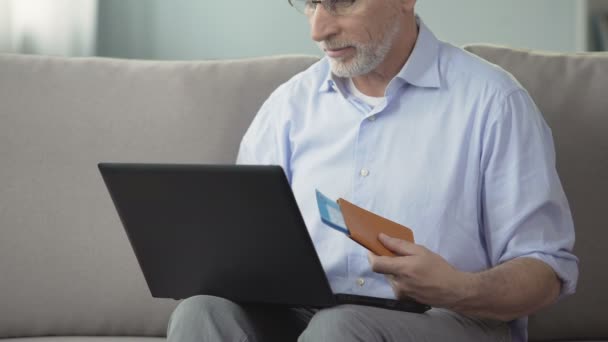 Homem em seus 60 anos a ver fotos da cidade resort, reserva quarto de hotel no laptop — Vídeo de Stock