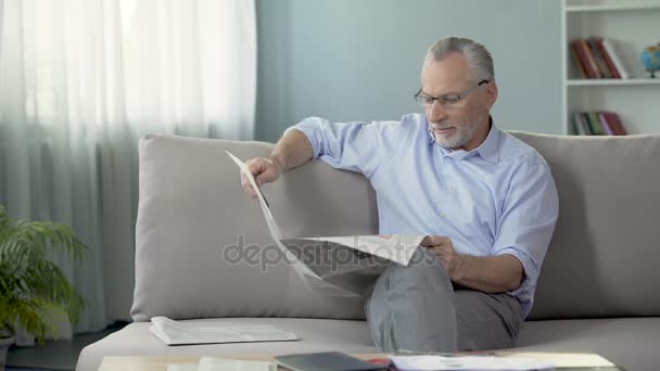 Starý muž sedí na pohovce a číst noviny, tisk a novinky, doby odpočinku