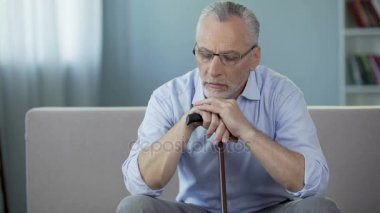 Baston üzerinde ellerini koyarak hasta adam kanepede oturan 50'li. Depresyon