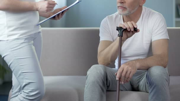 Enfermera anotando registros médicos, hablando con un viejo paciente masculino en el hospital — Vídeo de stock