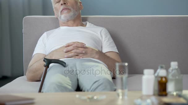 Ill grand-père solitaire dormir sur le canapé, médicaments debout sur la table — Video