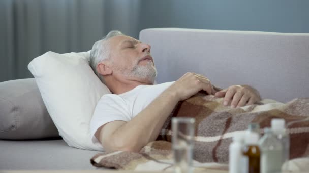 Hombre mayor durmiendo en el sofá, sufriendo de alta temperatura. Enfermedad — Vídeos de Stock