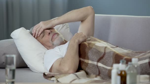 Starý člověk spí v posteli a trpící hrozné bolesti hlavy, nemoci
