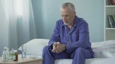 Hastalıktan kurtarmak için ilaç yatağın üstüne oturan hasta üst düzey adam üzgün
