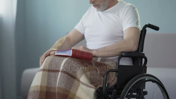 Alter Mann mit Behinderungen überprüft Album mit Fotos, vermisste Verwandte — Stockvideo