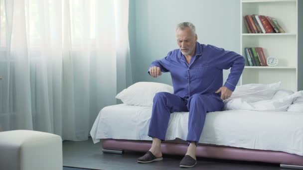 Senior férfi érzés éles fájdalom vissza ébredés után, rossz alvó feltételek — Stock videók