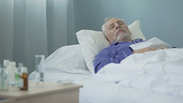 Zwakke mannelijke patiënt alert op ziekenhuisbed na het nemen van de dagelijkse dosis van de medicatie — Stockvideo