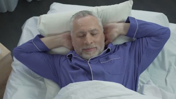 新しい整形外科マットレス、快適な睡眠に彼のベッドで日向ぼっこ長老 — ストック動画