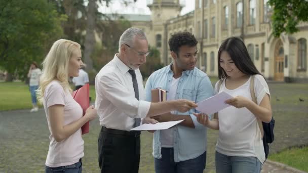 Profesor masculino dando exámenes a estudiantes multiétnicos y explicando resultados — Vídeo de stock