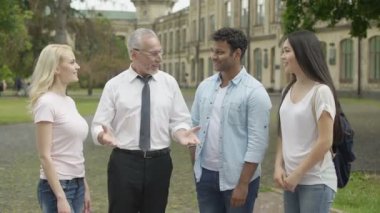 Mutlu öğretmen ve ellerini yığının üstüne koyarak çok ırklı öğrenciler takım bina