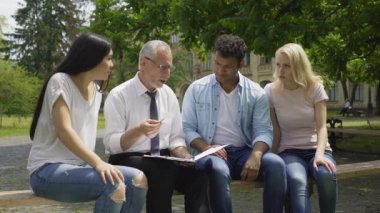 Grup çok ırklı öğrenci Fen öğretmen ile açık havada tartışıyor