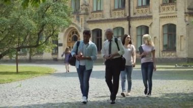 Çok etnik gruptan oluşan öğrenciler ve proje, tartışırken öğretmen Park'ta yürüyordunuz grup