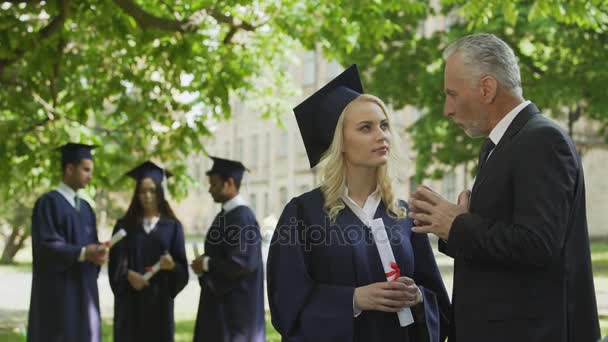 Decano hablando con hermosa mujer graduada cerca de la academia, carrera y futuro — Vídeo de stock