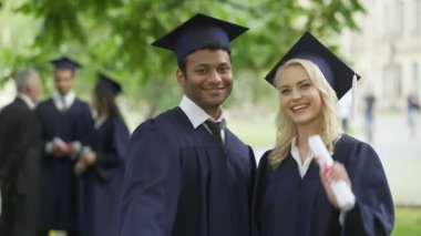 Diploma gösterilen ve gülümseyen, erkek ve kadın mezunları tamamlamak yüksek eğitim