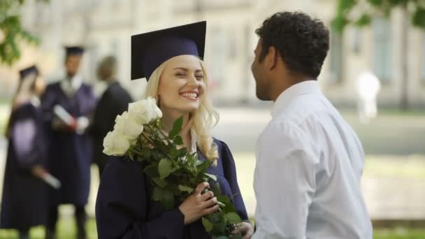 Парень дарит цветы своей выпускнице и обнимает специальное событие — стоковое видео
