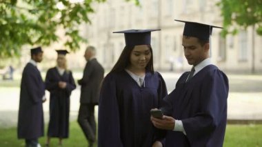 Erkek mezunu bir şey sınıf arkadaşı kadın için uygulama cep telefonu üzerinde gösterilen