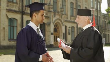 El mezuniyet günü sallayarak erkek öğrenciye diploma veren Üniversitesi Rektör