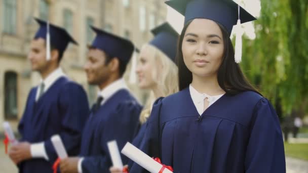 Ázsiai végzős hallgató az oklevél, mosolyogva a kamerába, nemzetközi tanulmányok — Stock videók