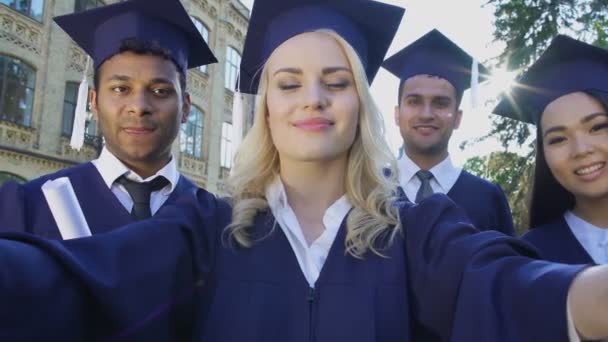 Klasgenoten in academische ornaat selfie overneemt graduatiedag, prestatie — Stockvideo