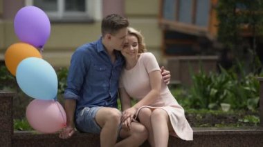 Adam kız arkadaşı onu yanağından, öpüşme, sarılma hava balonları ile sarılma