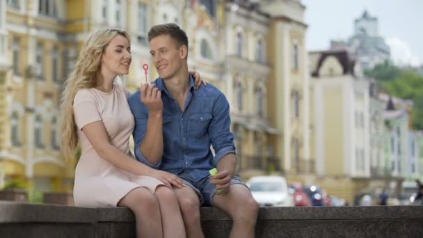 Mujer joven haciendo burbujas de jabón y besando a su novio, la felicidad y el romance — Vídeos de Stock