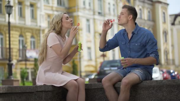 Jeune couple faisant des bulles de savon, se rejoignant pour s'embrasser, ludique — Video