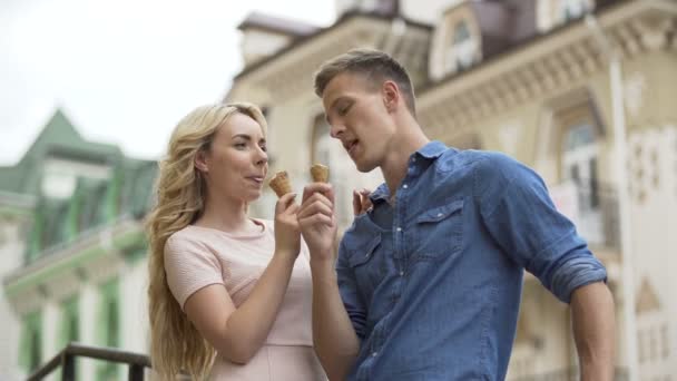 Hombre y mujer enamorados comiendo helado y mirándose, juguetones — Vídeo de stock