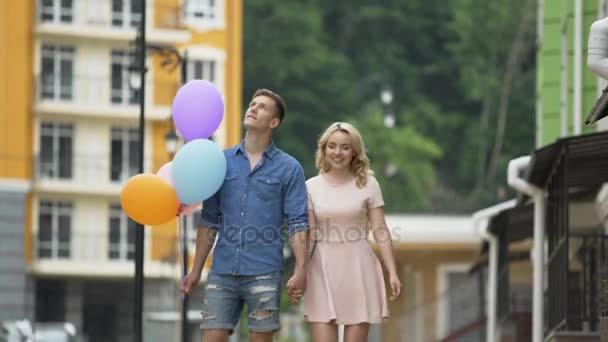 Fidanzata e fidanzato con palloncini che camminano per strada, fermandosi a baciare — Video Stock