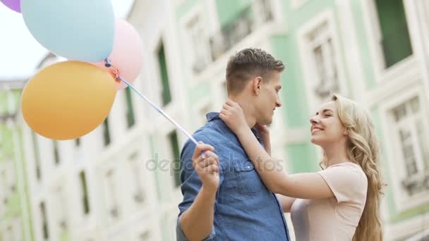 Pareja caminando por la calle, deteniéndose a besarse, tío sosteniendo globos, sentimientos — Vídeos de Stock