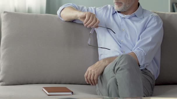 Досвідчений чоловік-психолог сидить на дивані, слухаючи пацієнта, сеанс — стокове відео