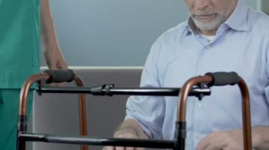 Yaşlı adam walker, adımları yapmak için ona yardım hemşire tutunarak ayakta