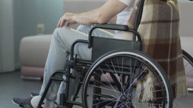 Erkek tekerlekli sandalye oturma ve dokunaklı onun diz, inconsolable tıbbi sonuç
