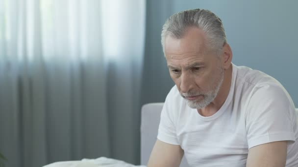 Viejo sentado en la cama, enfermera trayendo silla de ruedas, hombre mirando a la cámara — Vídeos de Stock