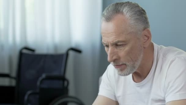 Senior mannen att ta piller, rullstol stående på bakgrunden, rehabilitering kurs — Stockvideo