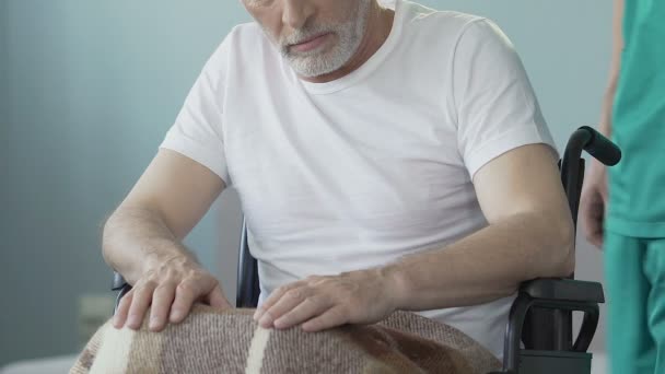 Viejo inmóvil sentado en silla de ruedas, enfermero atendiendo a paciente paralizado — Vídeos de Stock