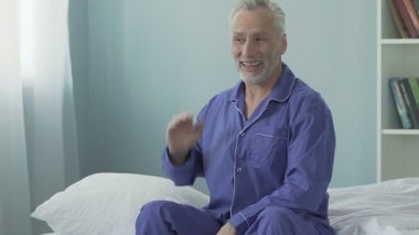 Yatak ve esneme, mutlu sabah, enerji dolu kenarında oturan üst düzey adam