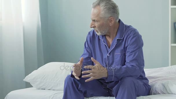 Vieil homme en colère assis sur son lit, regardant autour de lui avec suspicion, insatisfait, lunatique — Video
