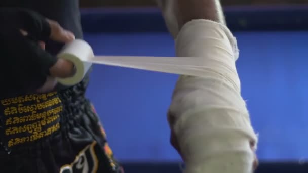 Wrestler carefully rewinding injured arm with elastic bandage before training — Stock Video