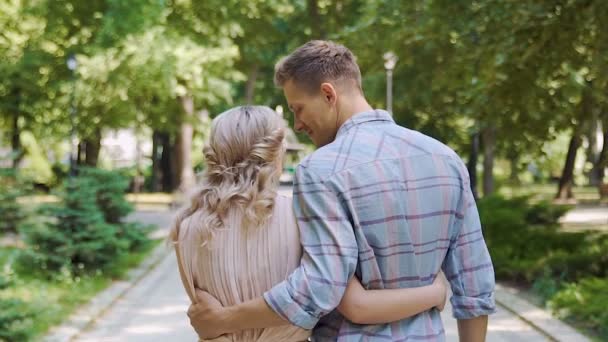 Giovane uomo e donna innamorati che camminano nel parco estivo, vista posteriore, rallentatore — Video Stock