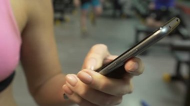 Genç bayan spor salonunda, smartphone hakkında bilgi arıyorum Fitness app kaydırma