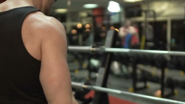 Cara muscular fazendo elevadores com barra de cachos no ginásio, treino ativo, musculação — Vídeo de Stock