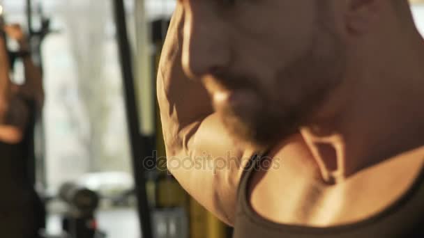 Killen gör bakre pull-downs med ansträngda ansikte, med stora vikter i gymmet, träning — Stockvideo