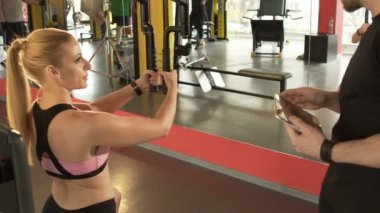 Göğüs sinek egzersiz yaparak, kişisel antrenör tablet ellerde ile konuşurken bir kadın