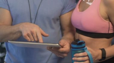 Eğitmen gösteren tablet ekranına kadın müşteri içme suyu spor şişe