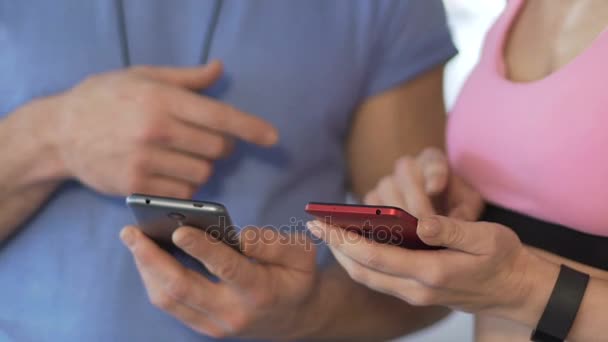 Feminino e seu personal trainer sincronizando celulares antes de iniciar o treino — Vídeo de Stock