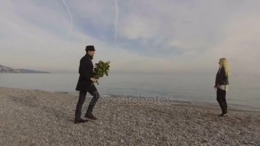 Denizde kıyıya, adam onu çiçeklerle, sunma bekleyen kadın çift öpüşme