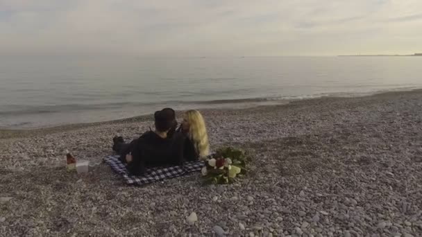 Coppia sdraiata su coperta sulla spiaggia e parlando, onde che rotolano sulla riva del mare, appuntamento — Video Stock
